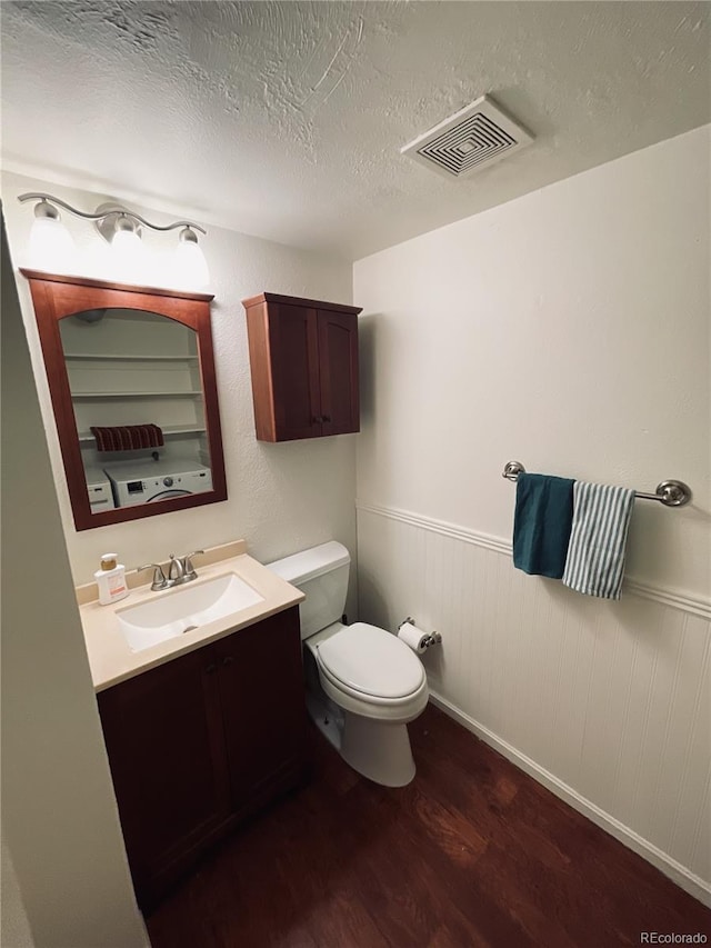 half bathroom with toilet, wainscoting, visible vents, wood finished floors, and vanity