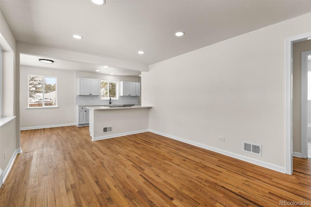 7555 E 22nd Ave, Denver, CO 80207 - unfurnished living room featuring light wood-style flooring, recessed lighting, baseboards, and a sink