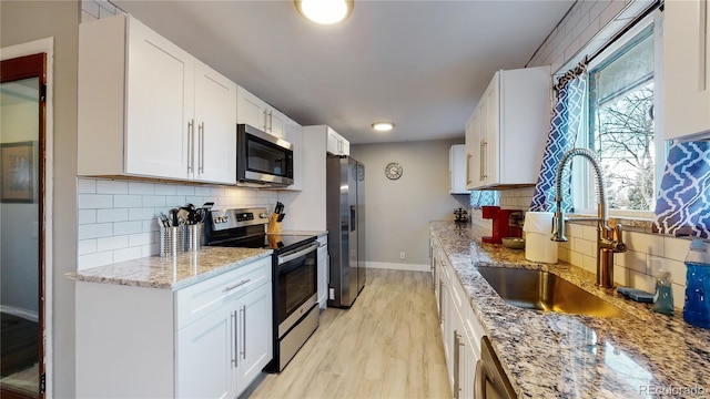 kitchen featuring white cabinets, light wood-type flooring, stainless steel appliances, and sink