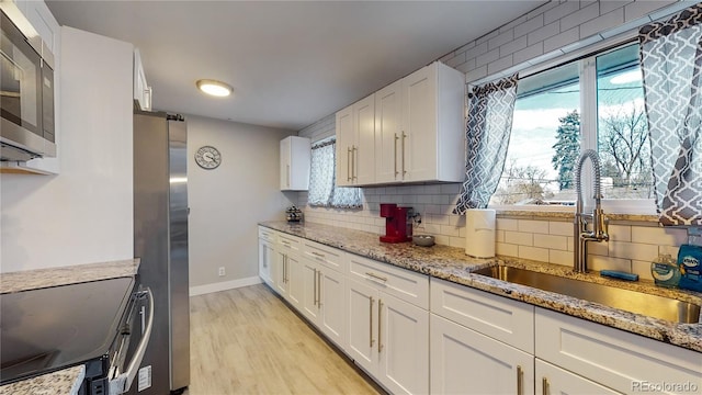 kitchen featuring sink, white cabinetry, stainless steel appliances, and light wood-type flooring