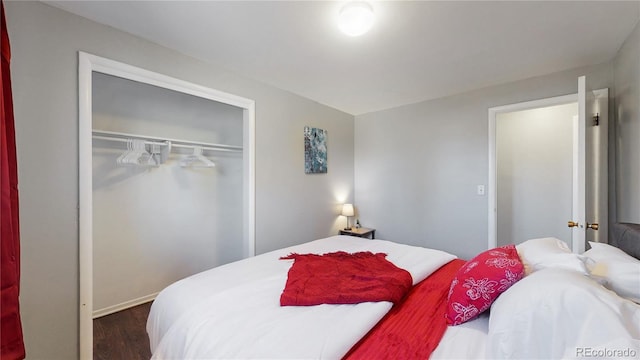 bedroom with dark hardwood / wood-style flooring and a closet