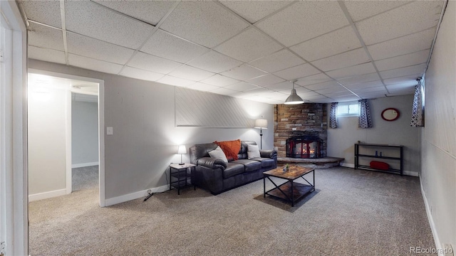 living room with a paneled ceiling, carpet flooring, and a wood stove