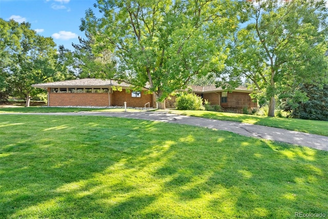 view of front of home featuring a front yard, brick siding, and driveway