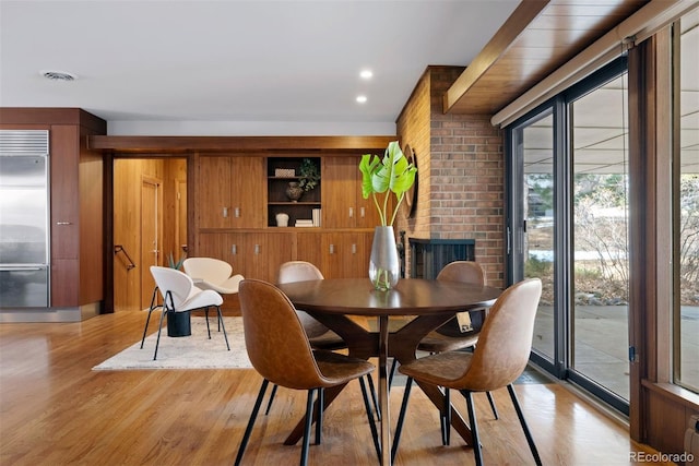 dining room with wood walls, light wood-type flooring, visible vents, and recessed lighting