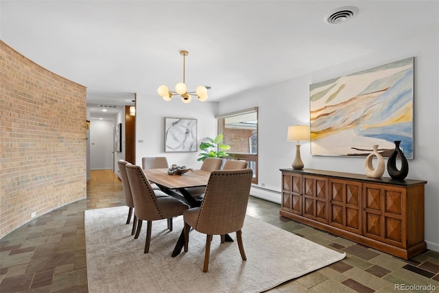 dining space featuring a notable chandelier, visible vents, a baseboard heating unit, stone finish flooring, and brick wall