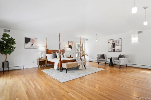 bedroom featuring a baseboard heating unit, light wood-style flooring, and visible vents