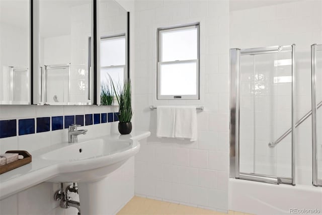 bathroom featuring combined bath / shower with glass door and a sink