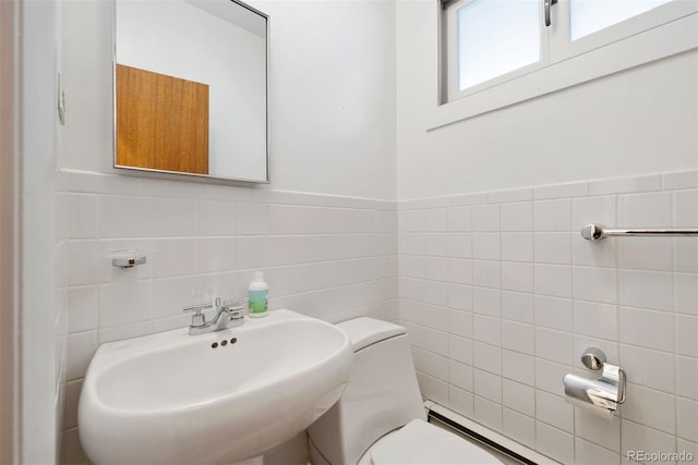 half bath featuring a sink, tile walls, and toilet