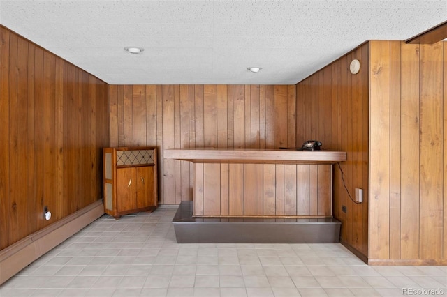 bar featuring light tile patterned floors, baseboard heating, and wooden walls