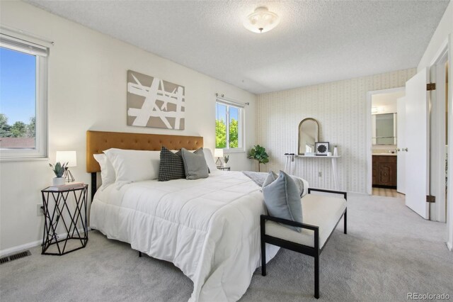 1791 S Laredo St, Aurora, CO 80017 - bedroom with carpet flooring, a textured ceiling, wallpapered walls, and ensuite bath
