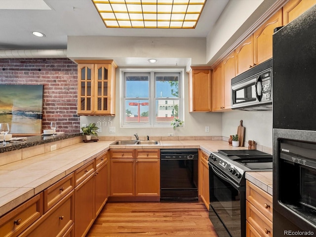 225 N Lincoln St Unit 4, Denver, CO 80203 - kitchen with black appliances, glass insert cabinets, light wood-style floors, tile countertops, and recessed lighting