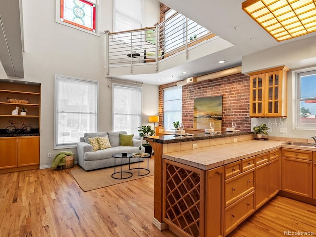 225 N Lincoln St Unit 4, Denver, CO 80203 - kitchen featuring a peninsula, glass insert cabinets, light wood finished floors, healthy amount of natural light, and a high ceiling