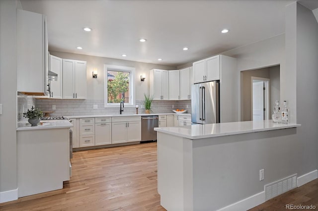 5838 S Louthan St, Littleton, CO 80120 - kitchen with appliances with stainless steel finishes, light wood-style flooring, decorative backsplash, white cabinets, and recessed lighting