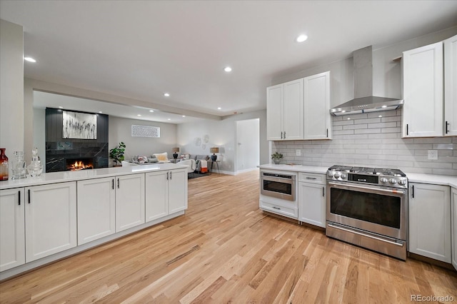 5838 S Louthan St, Littleton, CO 80120 - kitchen with appliances with stainless steel finishes, wall chimney range hood, light wood-style flooring, open floor plan, and recessed lighting