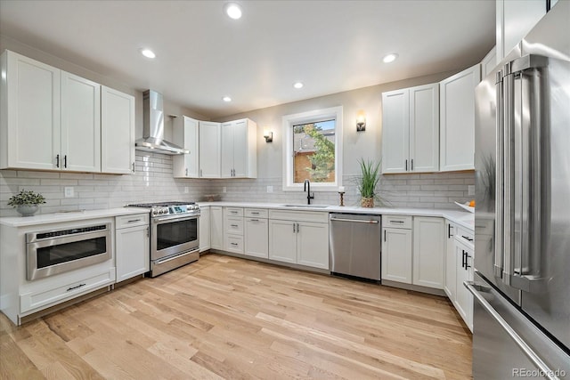 5838 S Louthan St, Littleton, CO 80120 - kitchen with appliances with stainless steel finishes, wall chimney range hood, light wood-type flooring, backsplash, and light countertops