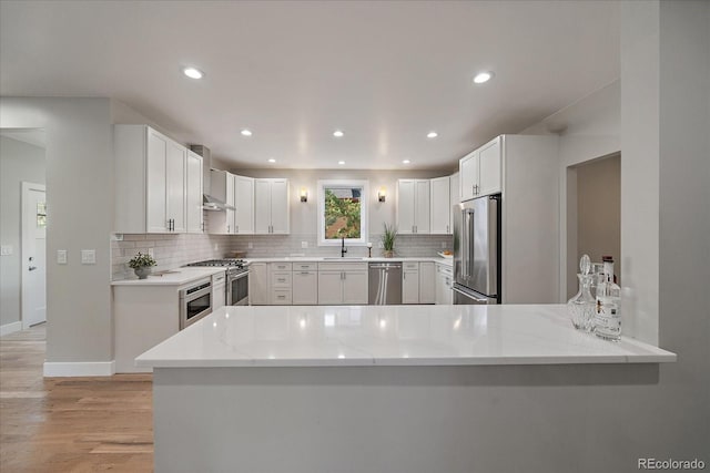 5838 S Louthan St, Littleton, CO 80120 - kitchen featuring high end appliances, wall chimney exhaust hood, backsplash, light stone countertops, and light wood finished floors