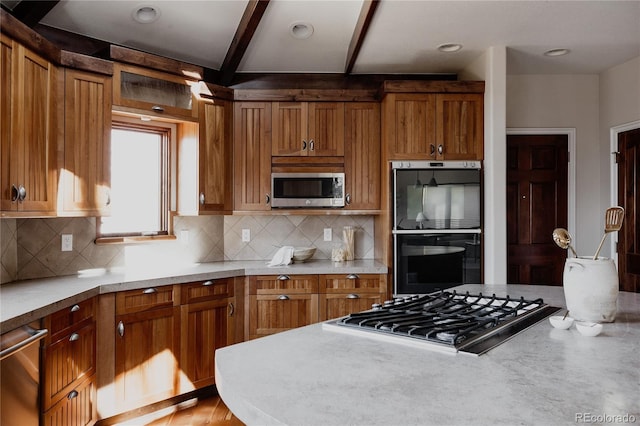 kitchen with brown cabinets, tasteful backsplash, appliances with stainless steel finishes, and light countertops