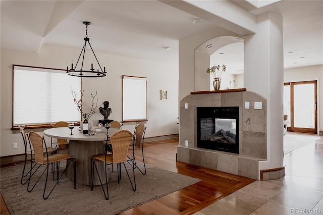 dining area featuring baseboards, an inviting chandelier, wood finished floors, and a fireplace