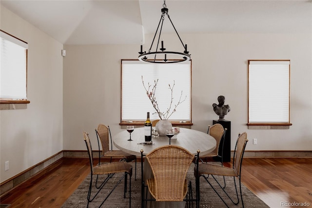 dining space featuring a chandelier, vaulted ceiling, baseboards, and wood finished floors