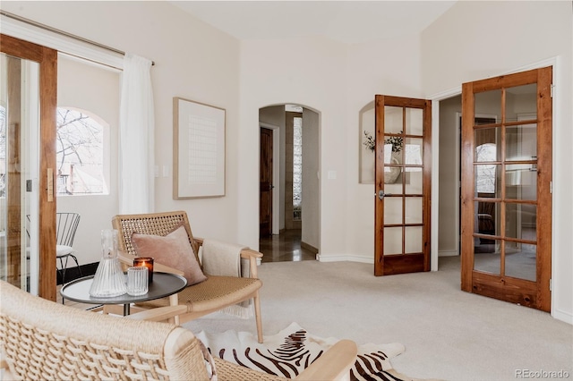 living area with arched walkways and carpet