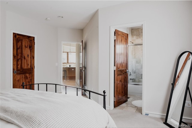 bedroom featuring ensuite bath, baseboards, and light carpet