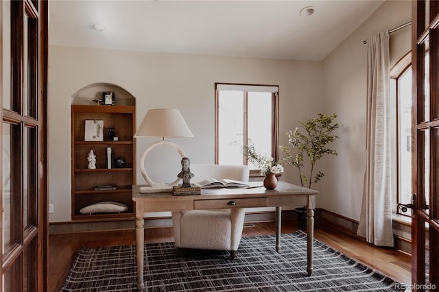 office space featuring built in shelves, wood finished floors, and baseboards