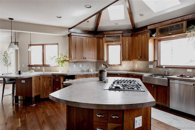 kitchen featuring dark wood finished floors, stainless steel appliances, a kitchen bar, and a sink