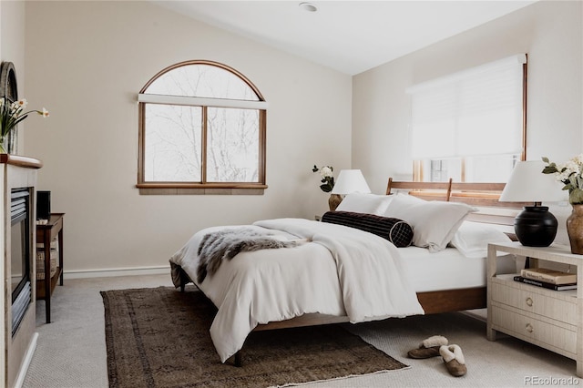 bedroom featuring baseboards, carpet floors, a glass covered fireplace, and vaulted ceiling