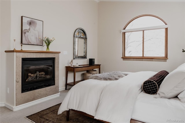 bedroom with baseboards, carpet floors, and a glass covered fireplace