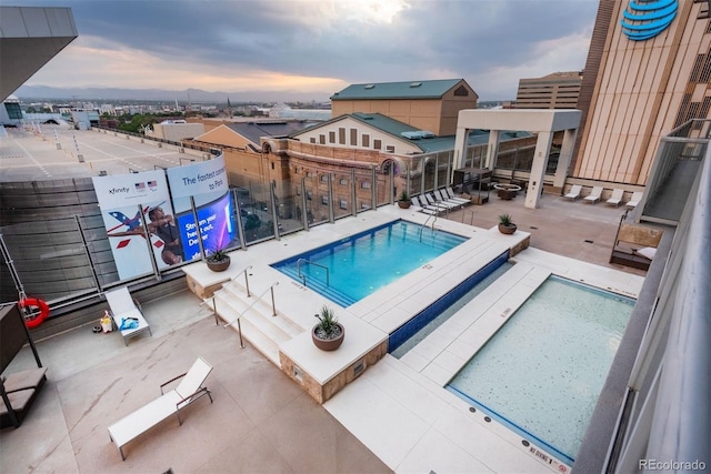 pool at dusk featuring a patio