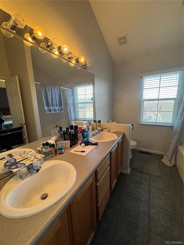 bathroom featuring toilet, vanity, vaulted ceiling, and tile patterned floors