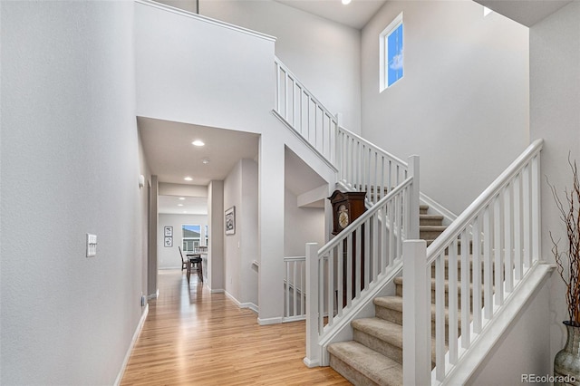 staircase with hardwood / wood-style flooring, a healthy amount of sunlight, and a high ceiling