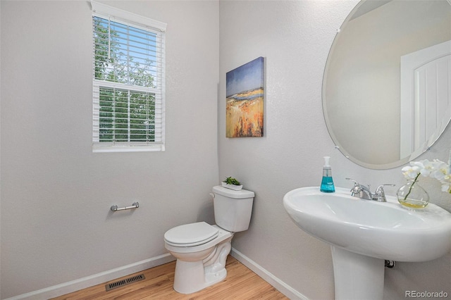 bathroom featuring wood-type flooring, toilet, and sink