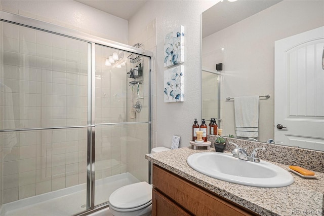 bathroom featuring an enclosed shower, vanity, and toilet