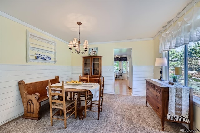 dining area featuring light carpet, wainscoting, an inviting chandelier, and crown molding