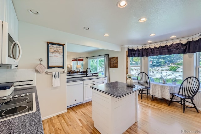 kitchen featuring dark countertops, white appliances, light wood-type flooring, and white cabinets