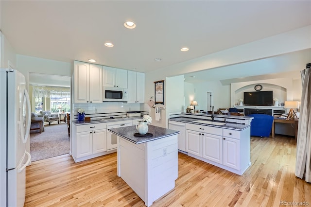 kitchen featuring white appliances, a kitchen island, and white cabinetry