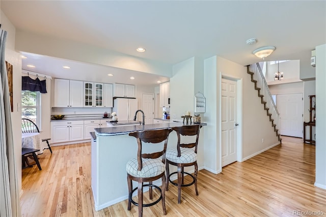 kitchen featuring white cabinets, dark countertops, glass insert cabinets, a kitchen breakfast bar, and freestanding refrigerator