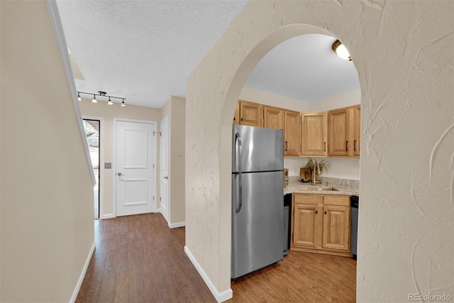 620 Macgregor Ave Unit 11, Estes Park, CO 80517 - kitchen with stainless steel appliances, wood finished floors, arched walkways, a textured wall, and a textured ceiling