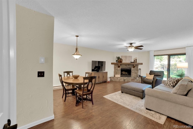 620 Macgregor Ave Unit 11, Estes Park, CO 80517 - living room featuring a ceiling fan, dark wood-style floors, a stone fireplace, a textured wall, and a textured ceiling