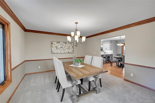 carpeted dining space featuring an inviting chandelier and ornamental molding