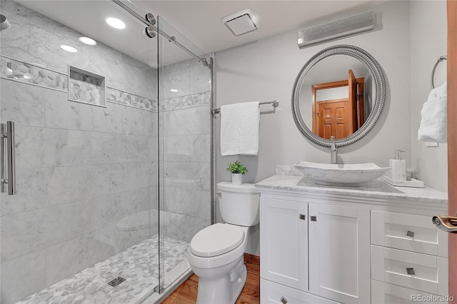 bathroom with vanity, toilet, hardwood / wood-style floors, and a tile shower