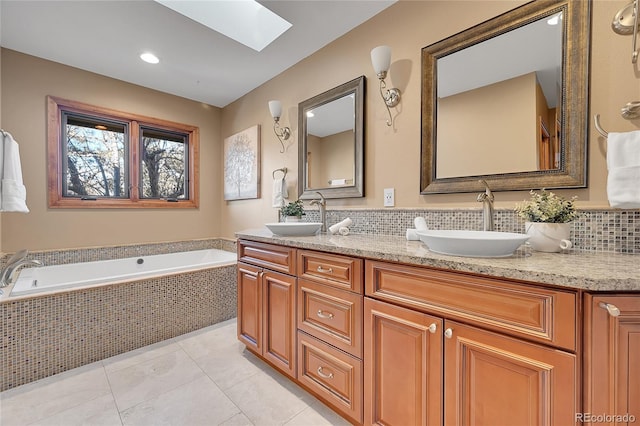 bathroom featuring tiled tub, vanity, tile patterned floors, and a skylight