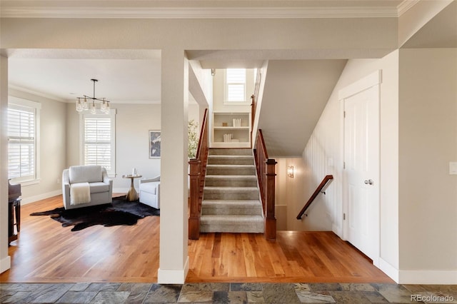 stairway with crown molding, a wealth of natural light, and wood-type flooring