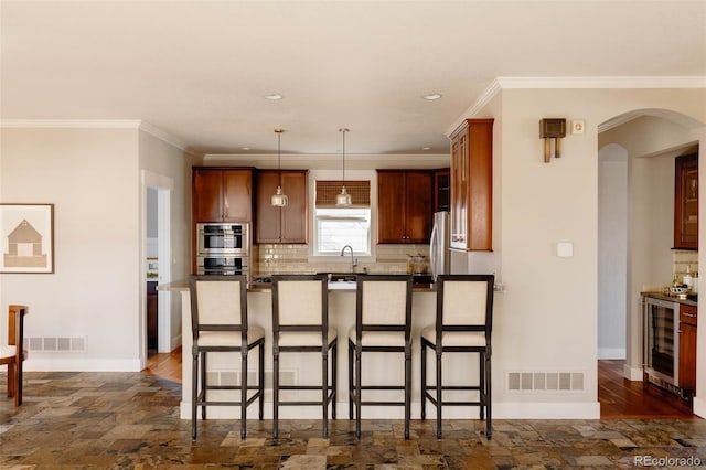 kitchen featuring decorative light fixtures, stainless steel fridge, a breakfast bar, decorative backsplash, and wine cooler