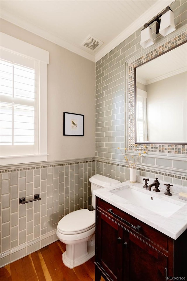 bathroom featuring toilet, crown molding, vanity, tile walls, and hardwood / wood-style flooring