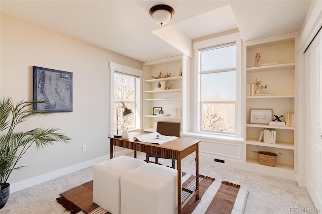 home office featuring built in shelves and light colored carpet