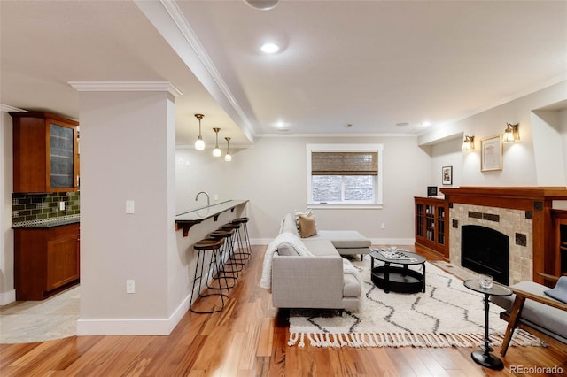 living room featuring a tile fireplace, crown molding, and light hardwood / wood-style flooring