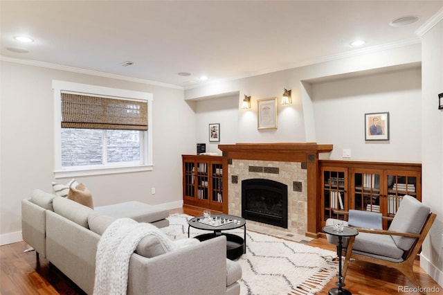 living room featuring a tiled fireplace, hardwood / wood-style floors, and ornamental molding