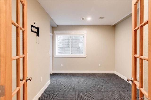 carpeted spare room featuring french doors